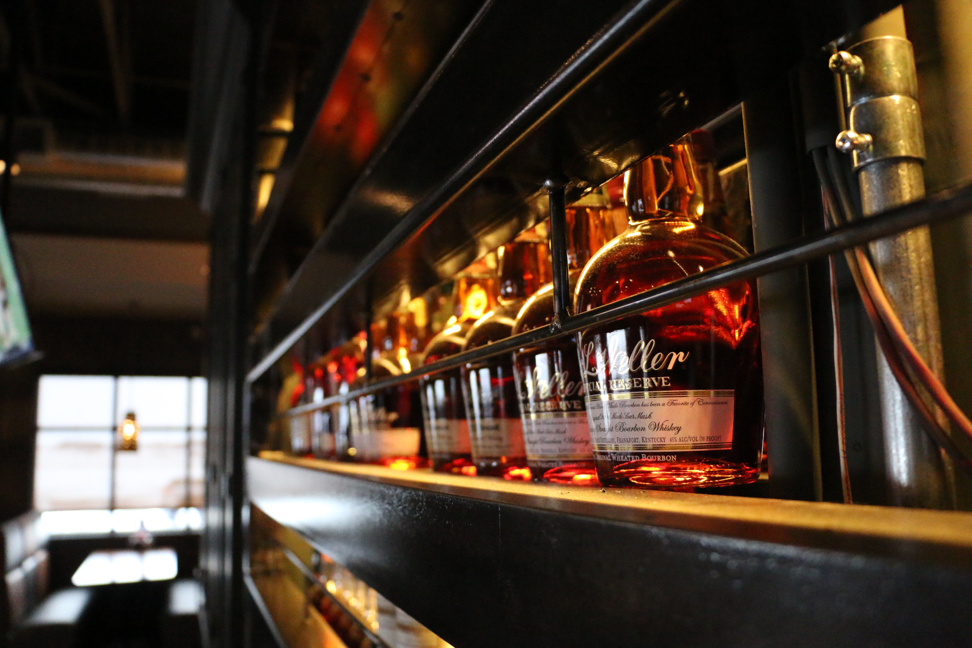 Warmly lit backbar lined with bourbon and whiskey bottles